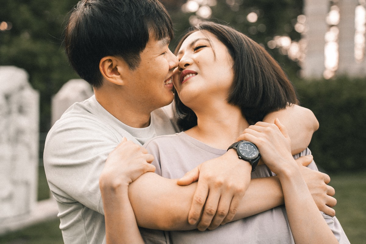 A man and woman hug in a garden, conveying love, romance, and happiness.