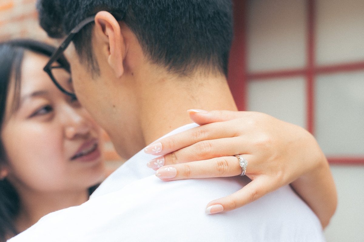 A man and woman about to kiss. It portrays a moment of love and affection between the couple with emphasis of her engagement ring.